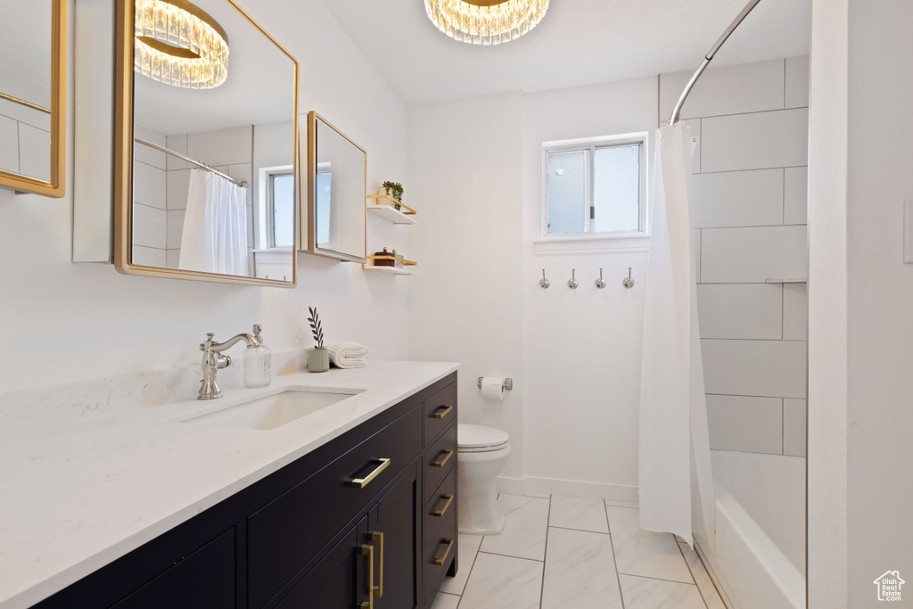 Bathroom featuring toilet, marble look tiles, and vanity