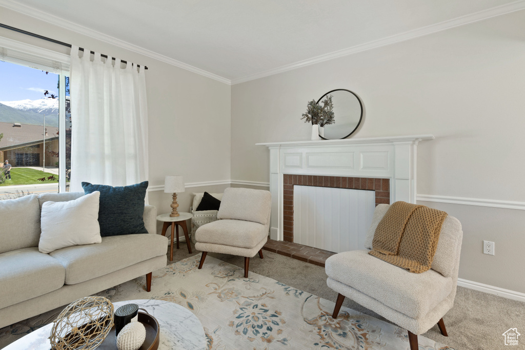 Carpeted living room featuring crown molding, baseboards, and a brick fireplace
