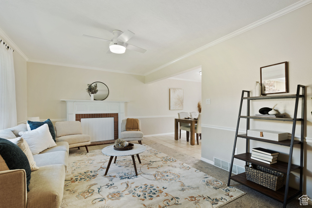Living area with ornamental molding, a ceiling fan, a brick fireplace, and baseboards