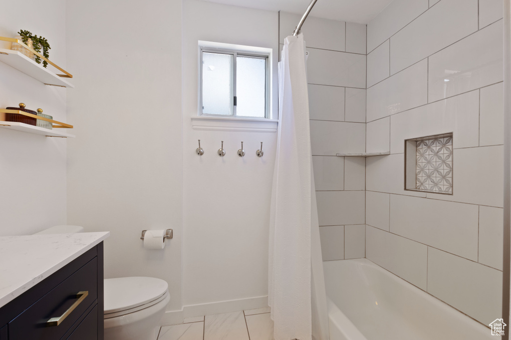 Bathroom featuring toilet, baseboards, vanity, and shower / tub combo with curtain