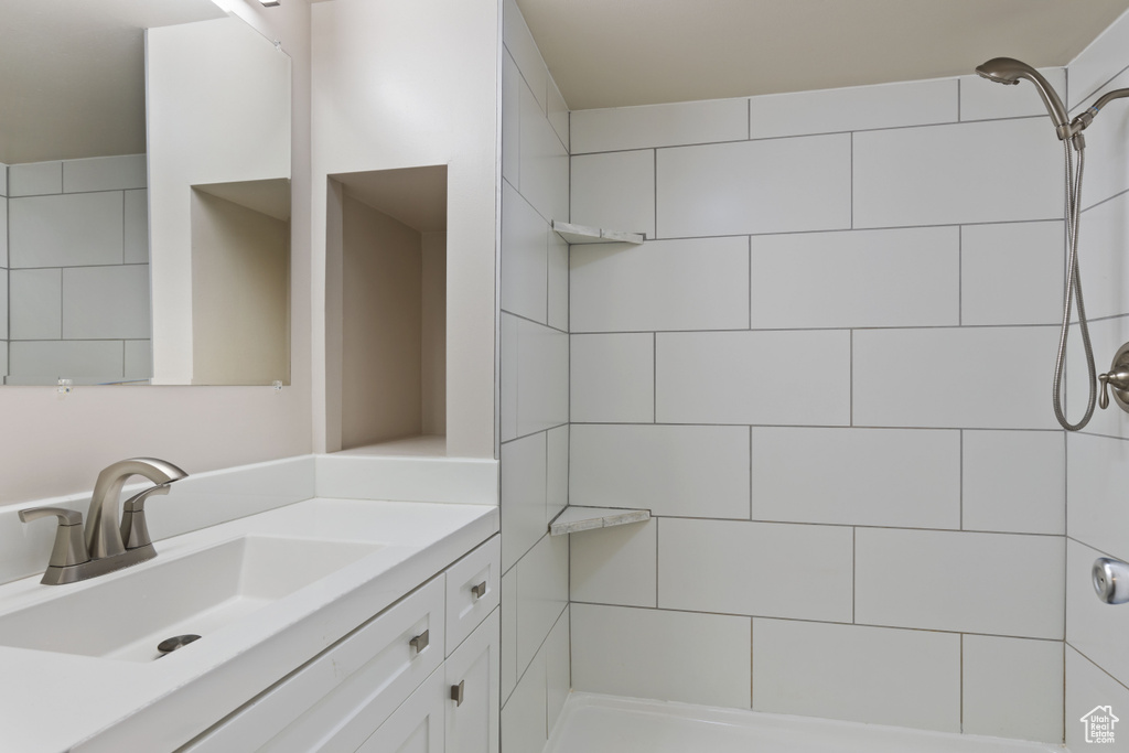 Bathroom featuring a tile shower and vanity