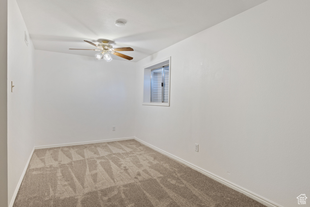 Spare room with carpet flooring, ceiling fan, baseboards, and a smoke detector