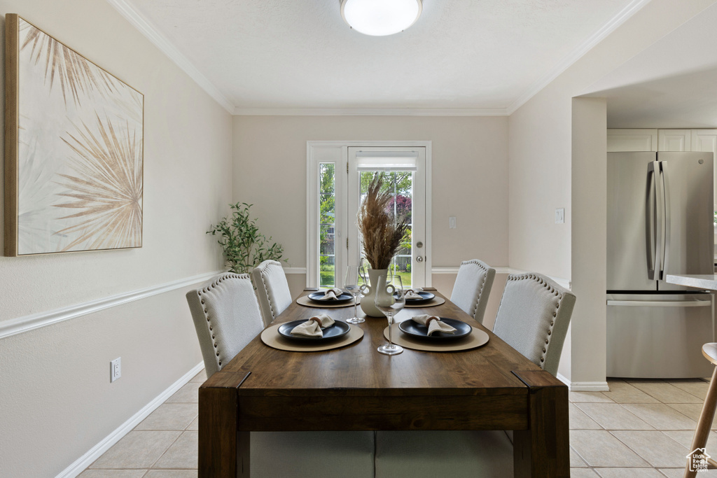 Dining room featuring light tile patterned floors, ornamental molding, and baseboards
