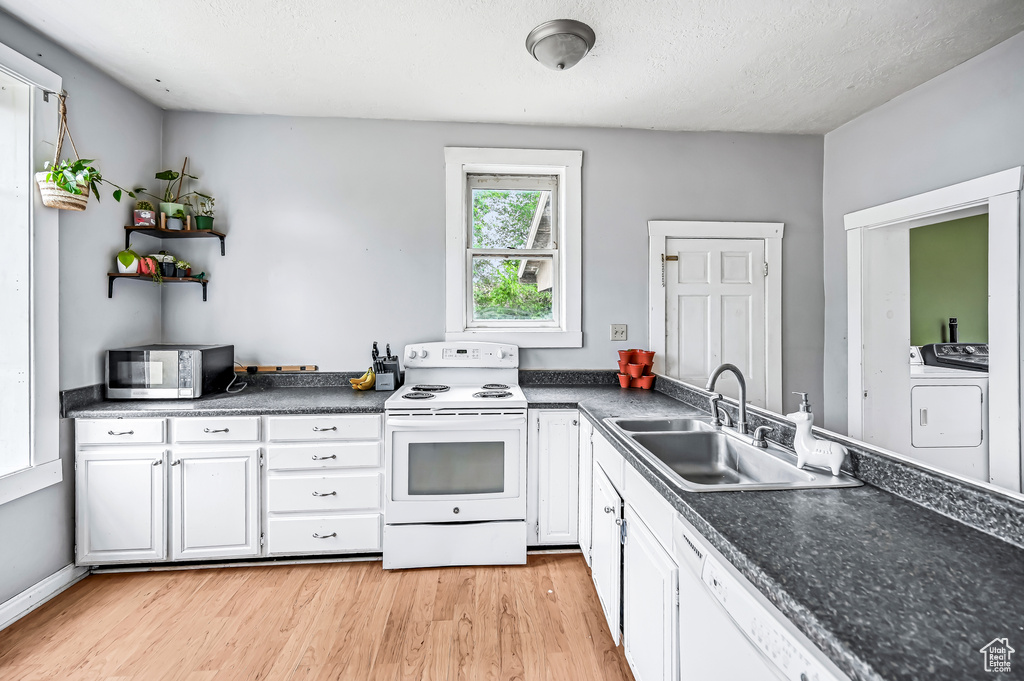 Kitchen featuring white appliances, a sink, washer and dryer, light wood-type flooring, and a textured ceiling