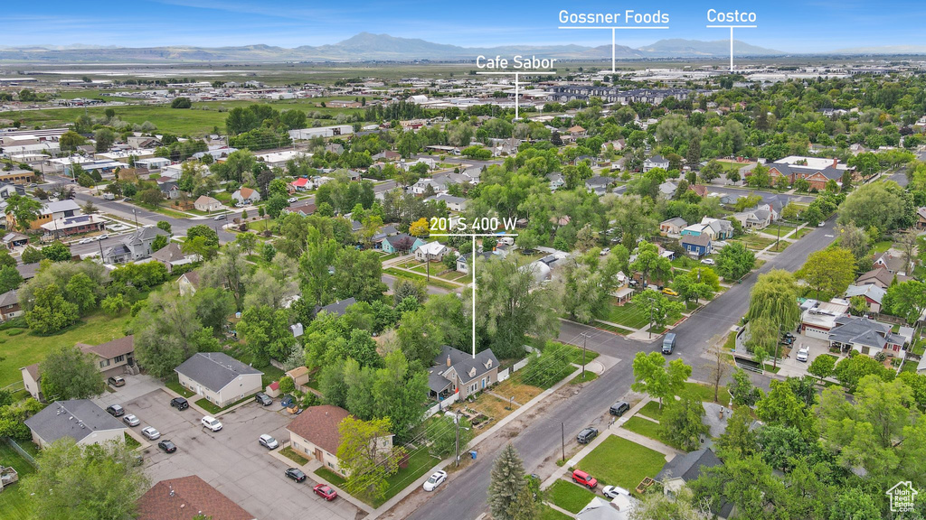 Aerial view of property and surrounding area featuring a mountain backdrop and nearby suburban area