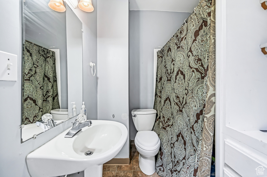 Bathroom with toilet, a sink, and tile patterned flooring