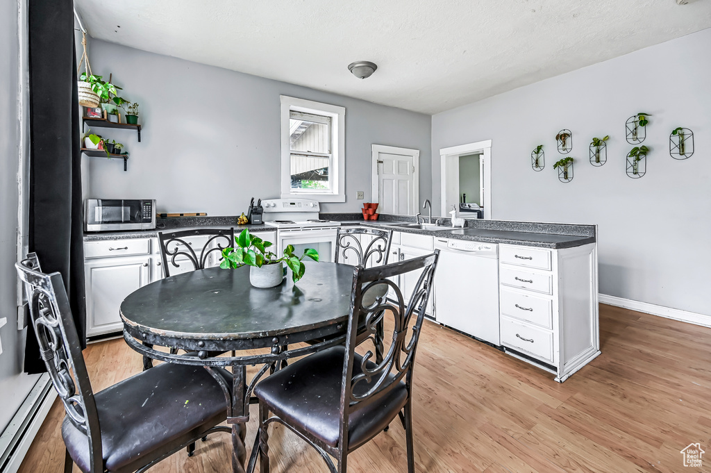 Dining space with light wood-type flooring, a baseboard heating unit, and baseboards