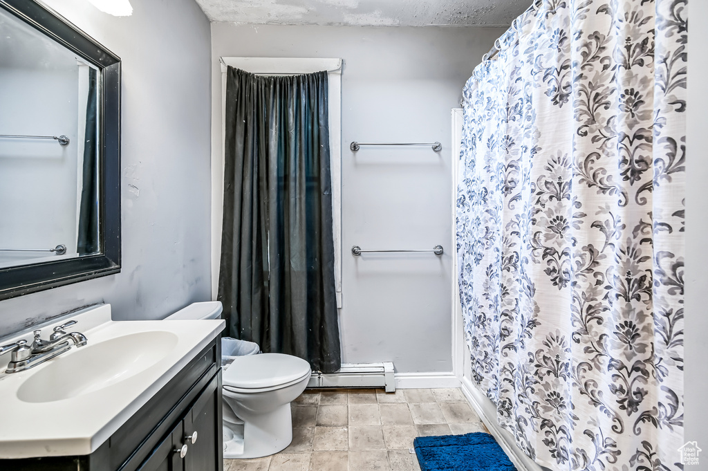 Full bathroom with a baseboard radiator, toilet, vanity, and curtained shower