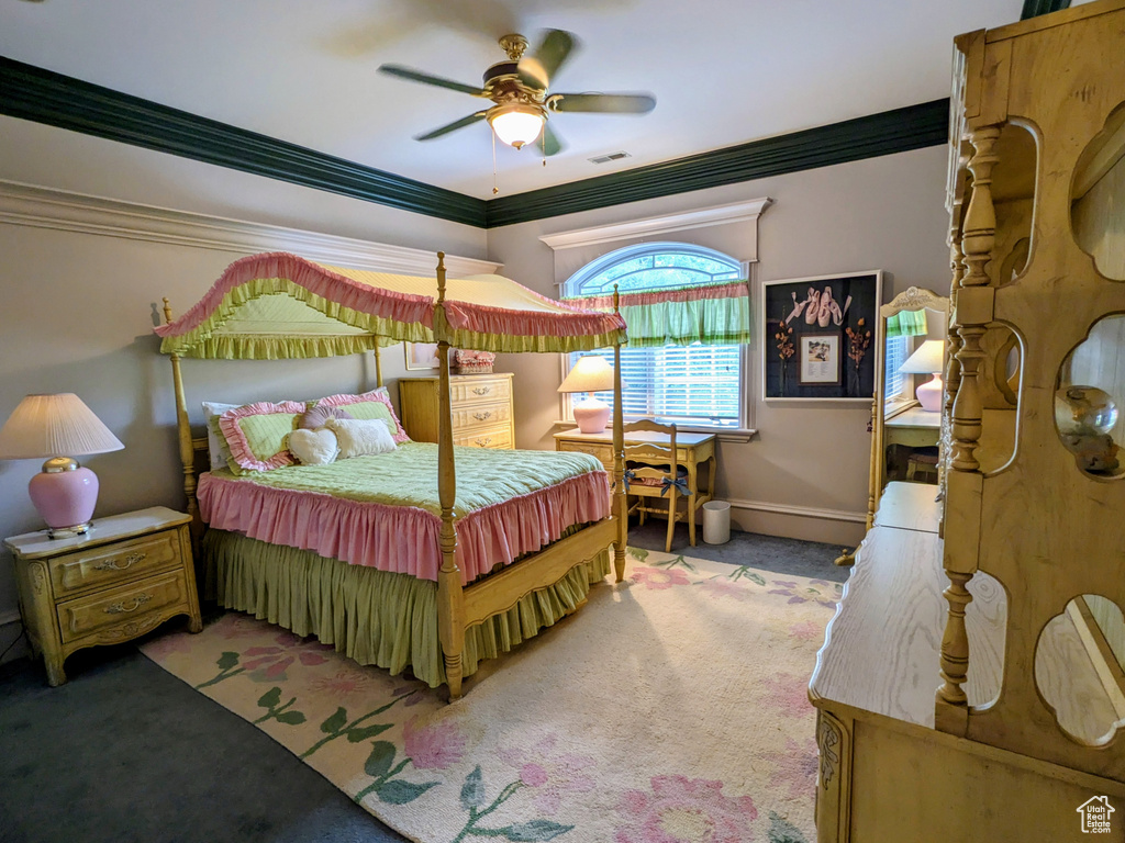 Carpeted bedroom featuring ornamental molding, a ceiling fan, and baseboards