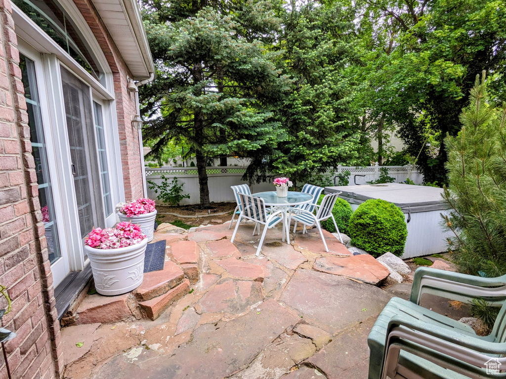 Fenced backyard featuring a patio area, outdoor dining area, and a hot tub