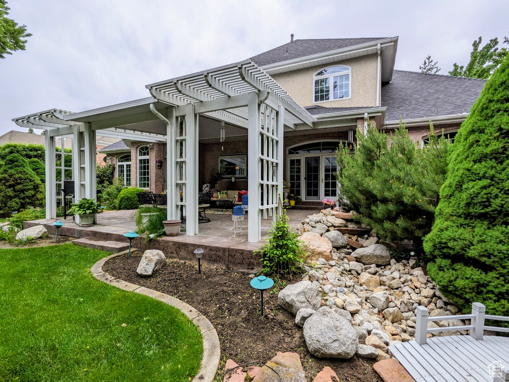 Rear view of property featuring a pergola, a patio, and stucco siding