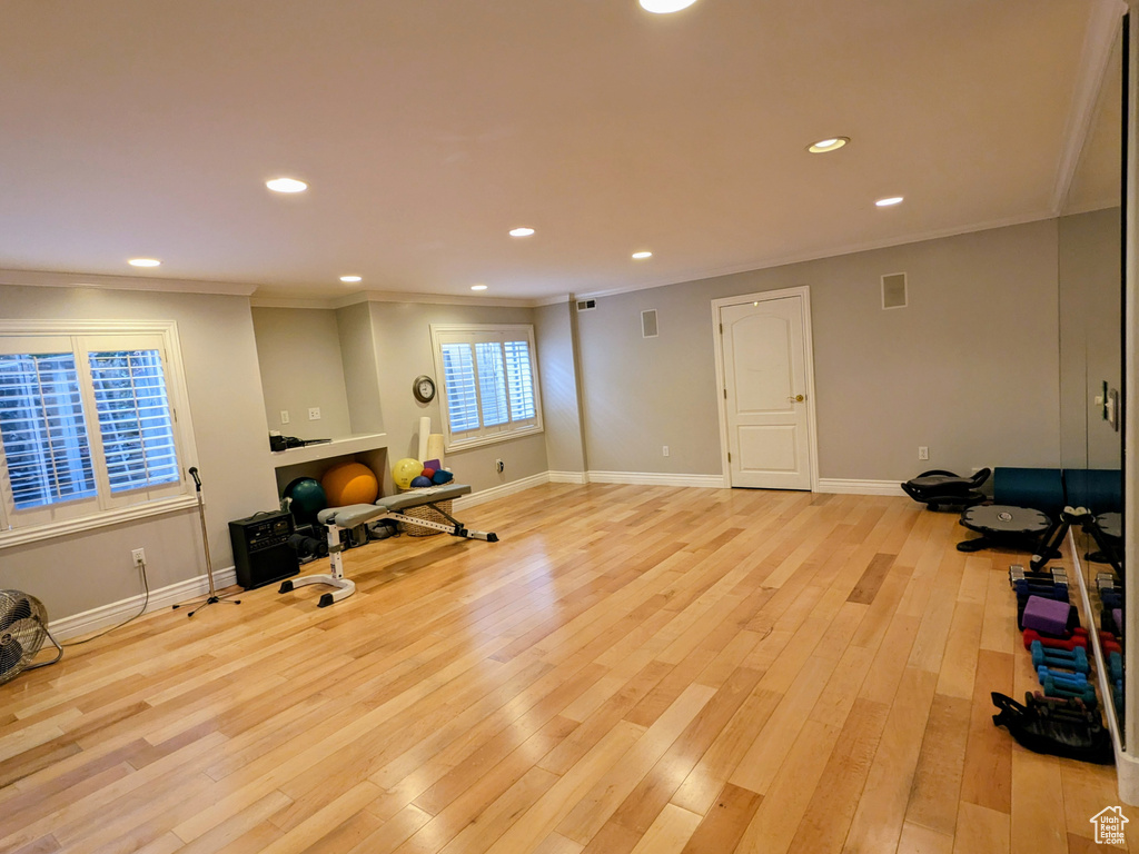 Exercise room with ornamental molding, recessed lighting, light wood-style flooring, and baseboards