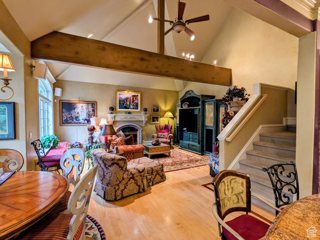 Living area with wood finished floors, ceiling fan, a fireplace, and stairway