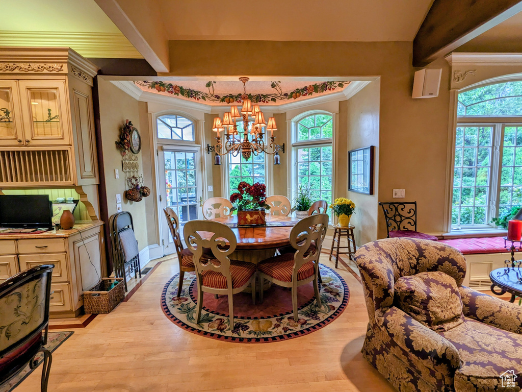 Dining space featuring a chandelier, ornamental molding, light wood finished floors, and baseboards