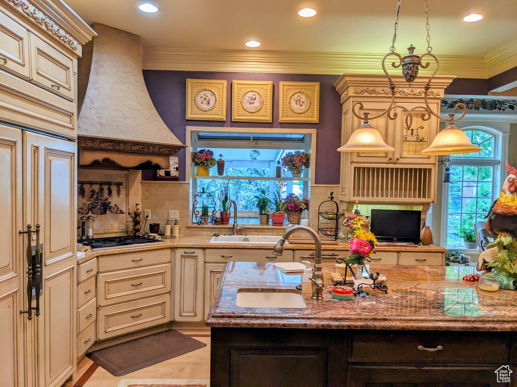 Kitchen featuring cream cabinets, custom exhaust hood, a sink, gas cooktop, and ornamental molding