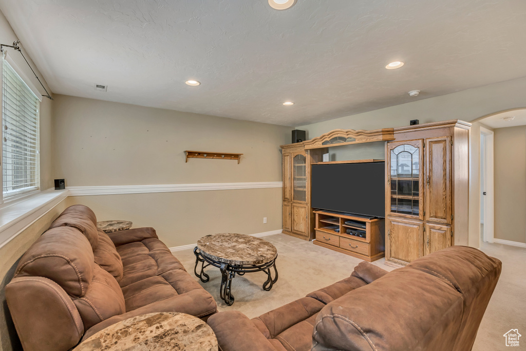 Living area with arched walkways, light colored carpet, recessed lighting, and baseboards