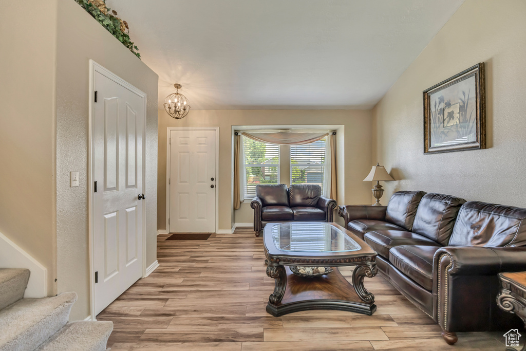 Living room featuring light wood finished floors, a chandelier, stairway, baseboards, and a textured wall