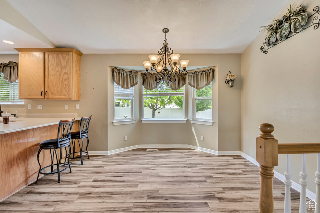 Kitchen featuring light wood-type flooring, healthy amount of natural light, and a chandelier