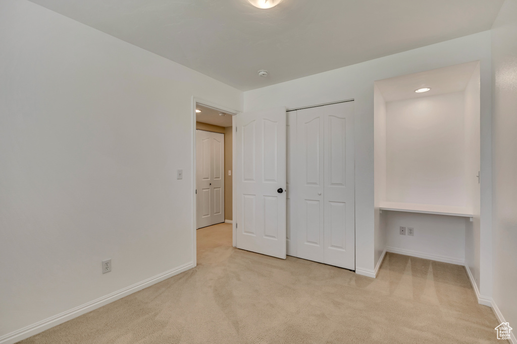 Unfurnished bedroom featuring light carpet, baseboards, a closet, and recessed lighting