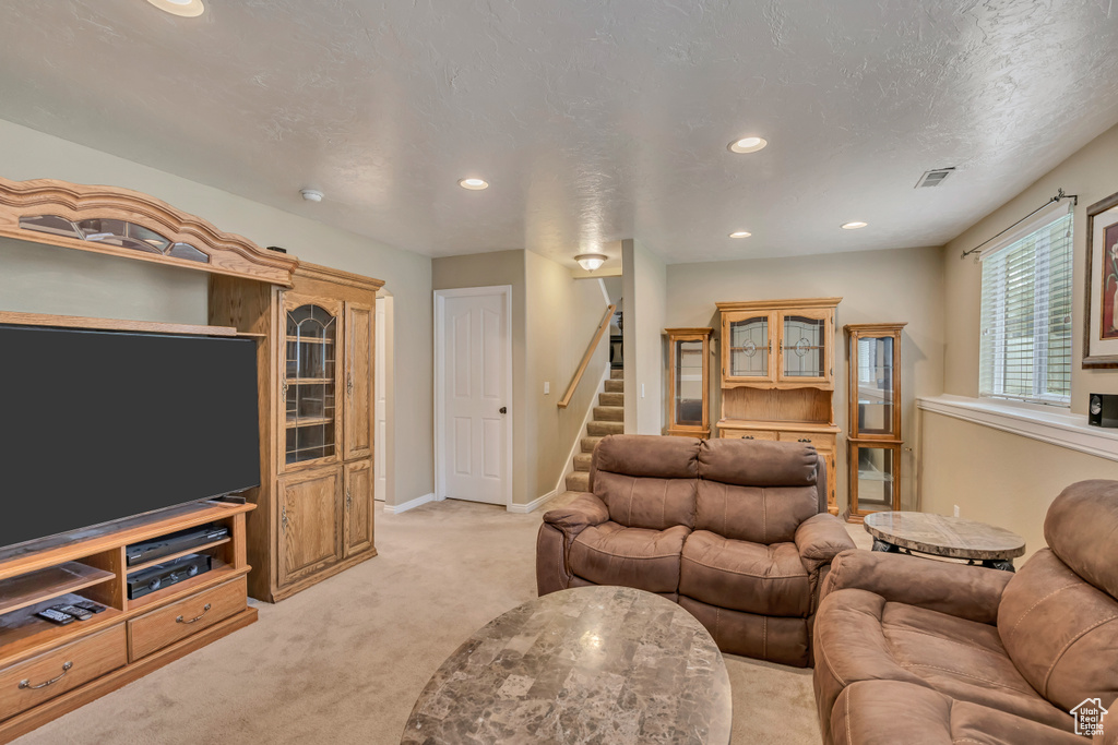 Living room featuring light carpet, stairs, recessed lighting, and baseboards