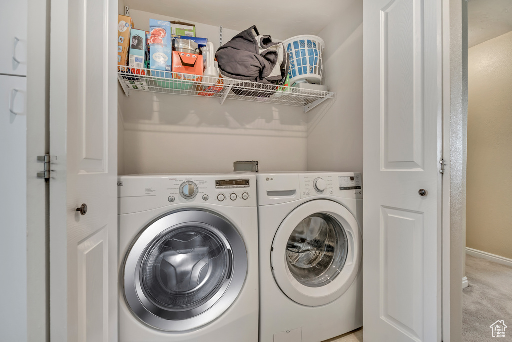 Laundry area featuring washing machine and clothes dryer and light colored carpet