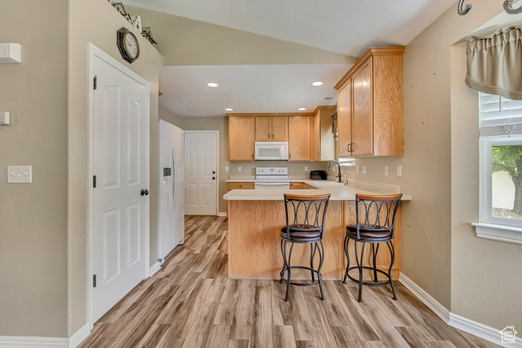 Kitchen with white appliances, light countertops, light wood-style flooring, a peninsula, and recessed lighting