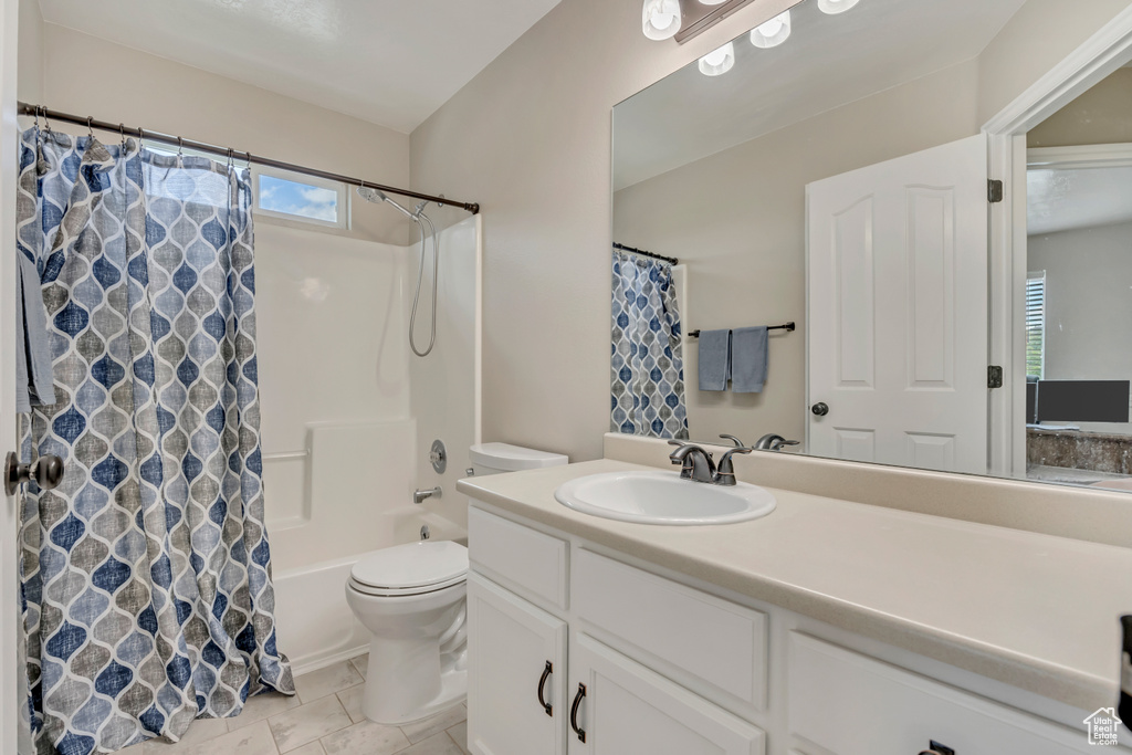 Bathroom featuring toilet, vanity, shower / bathtub combination with curtain, and tile patterned flooring