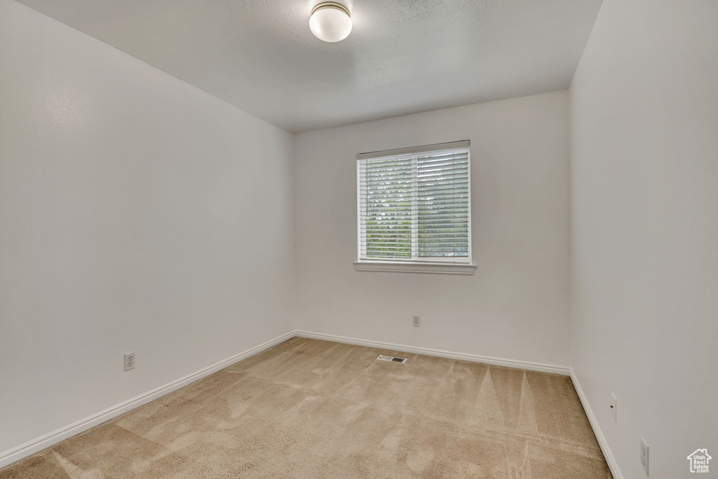 Empty room featuring light carpet and baseboards