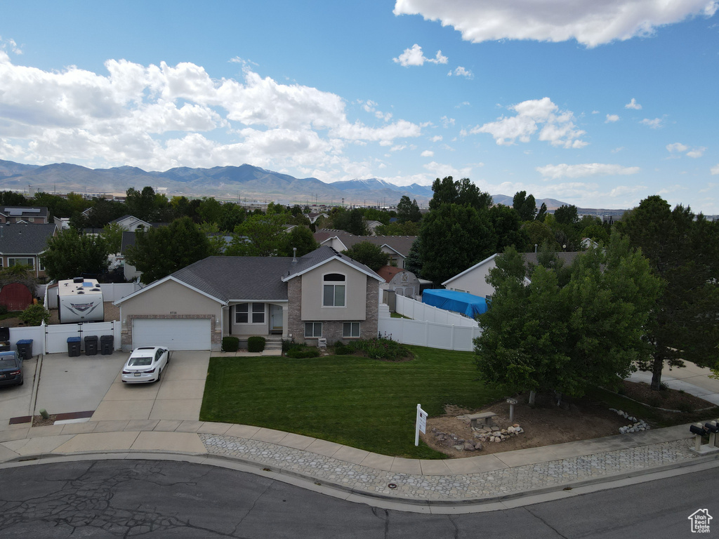 Tri-level home featuring driveway, an attached garage, a mountain view, and stucco siding