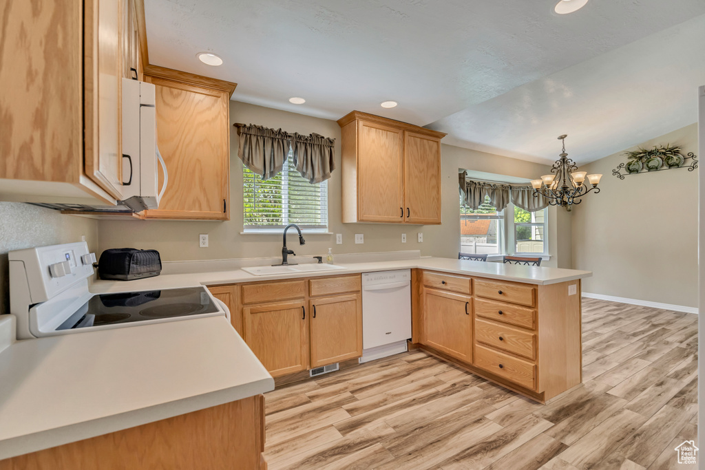 Kitchen with white appliances, a peninsula, a sink, light wood-style floors, and plenty of natural light