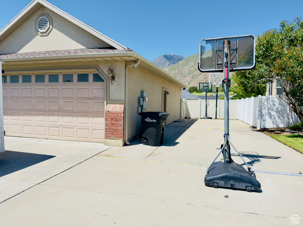 View of property exterior with a mountain view, stucco siding, concrete driveway, and brick siding