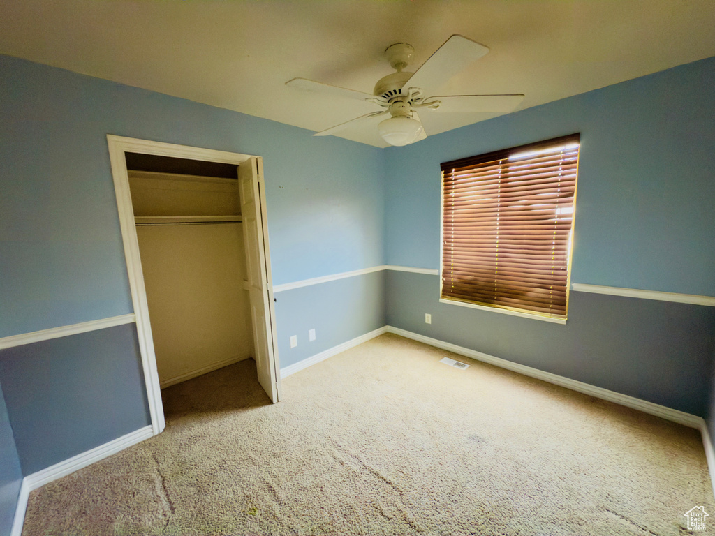 Unfurnished bedroom featuring carpet floors, baseboards, a closet, and ceiling fan