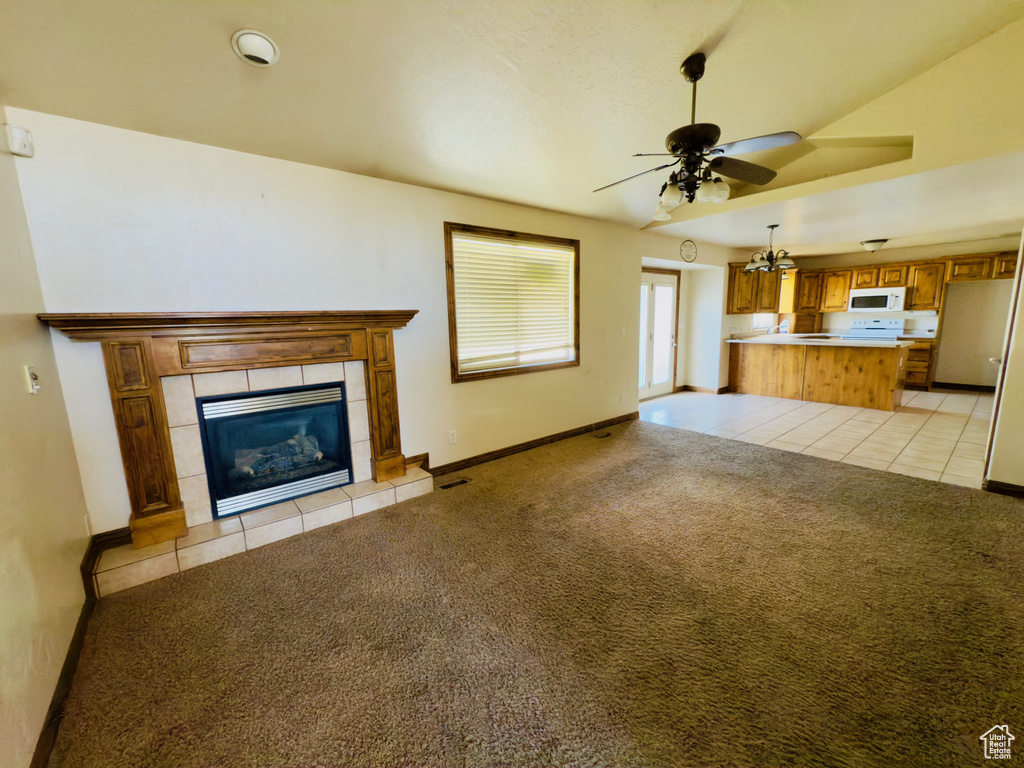Unfurnished living room with ceiling fan, light colored carpet, light tile patterned flooring, a tile fireplace, and baseboards