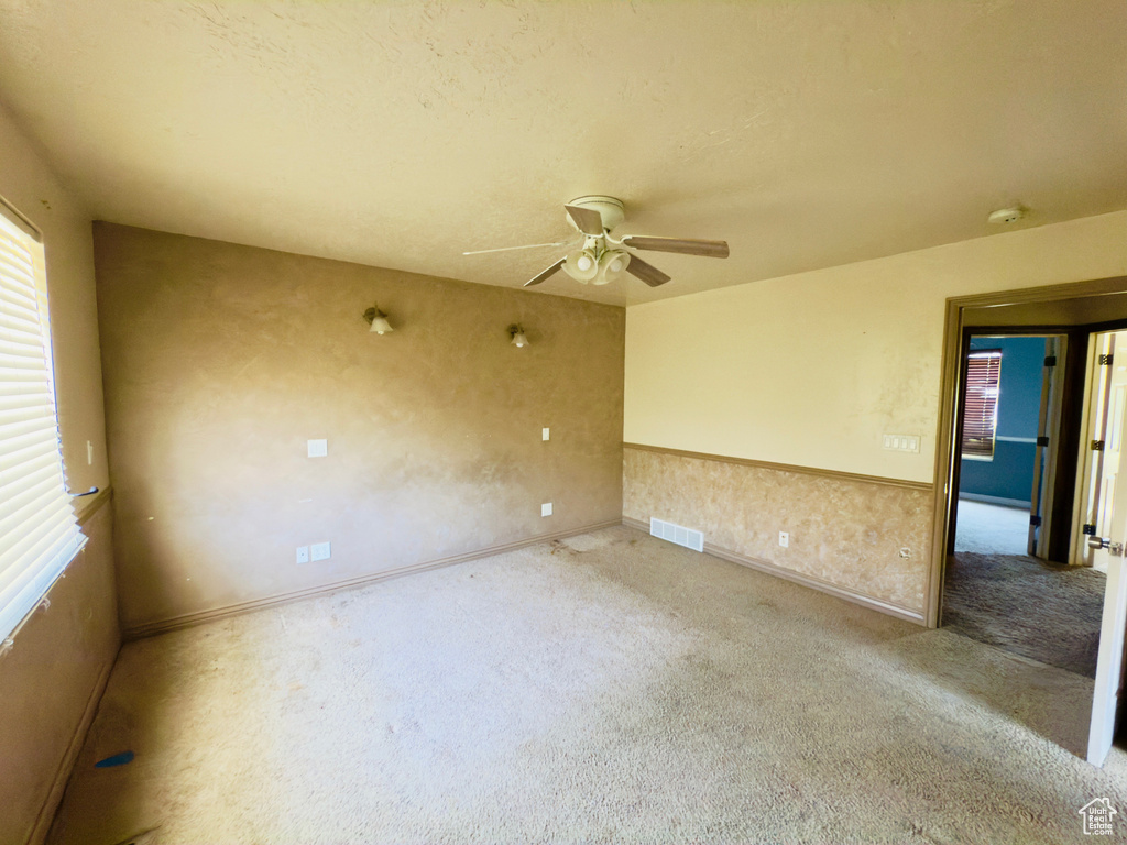 Carpeted empty room with a ceiling fan and baseboards