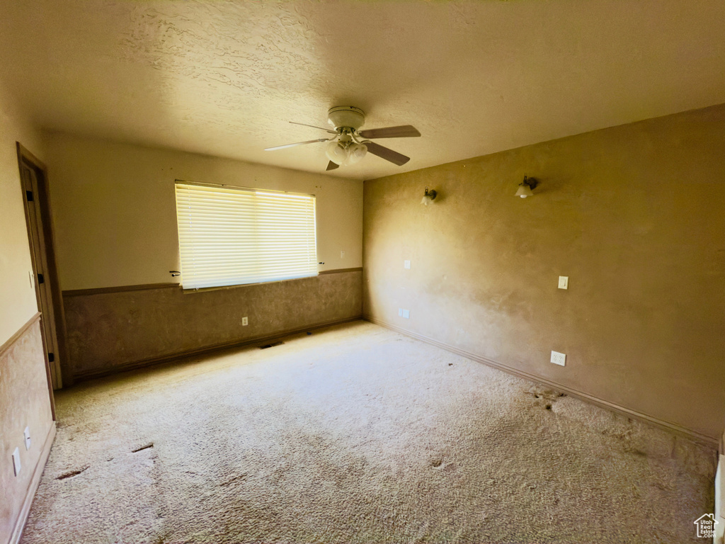 Carpeted spare room with ceiling fan and a textured ceiling