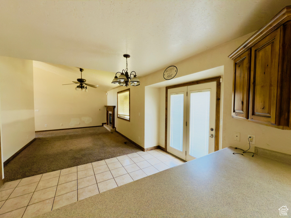 Kitchen featuring light carpet, a chandelier, hanging light fixtures, ceiling fan, and light tile patterned flooring