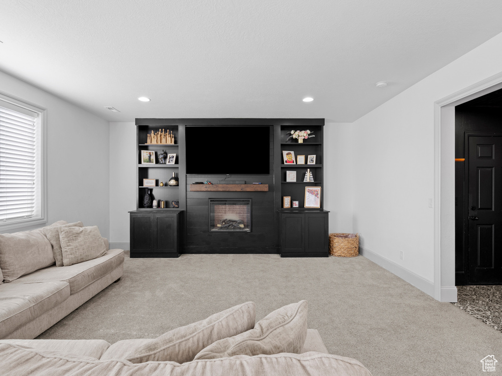 Living room featuring carpet flooring, a large fireplace, recessed lighting, baseboards, and built in shelves