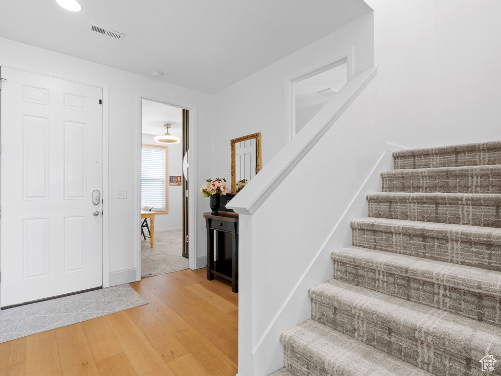 Foyer featuring stairs, light wood-style floors, and baseboards
