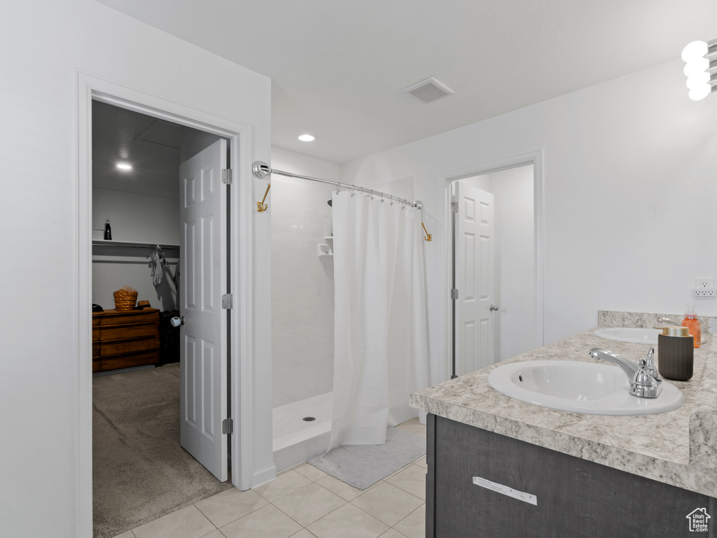 Full bath with a stall shower, tile patterned flooring, and double vanity