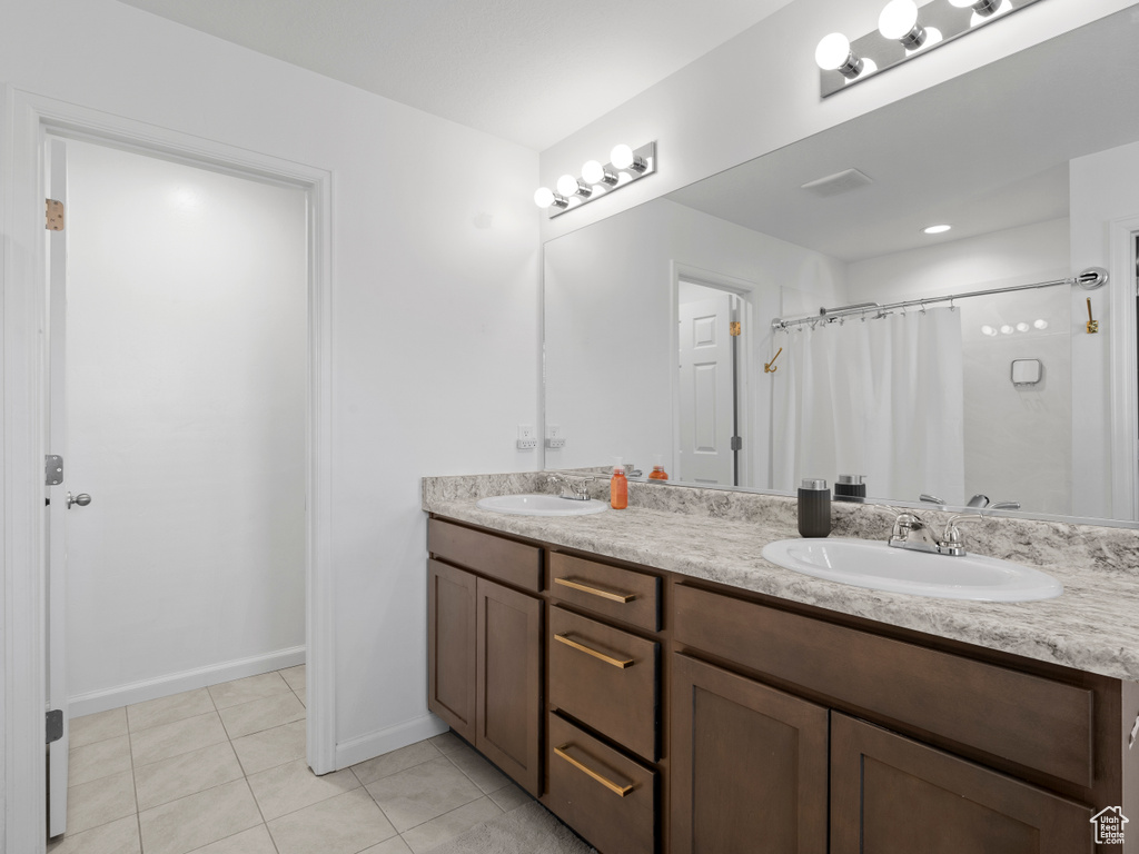 Bathroom featuring tile patterned flooring, double vanity, curtained shower, and baseboards