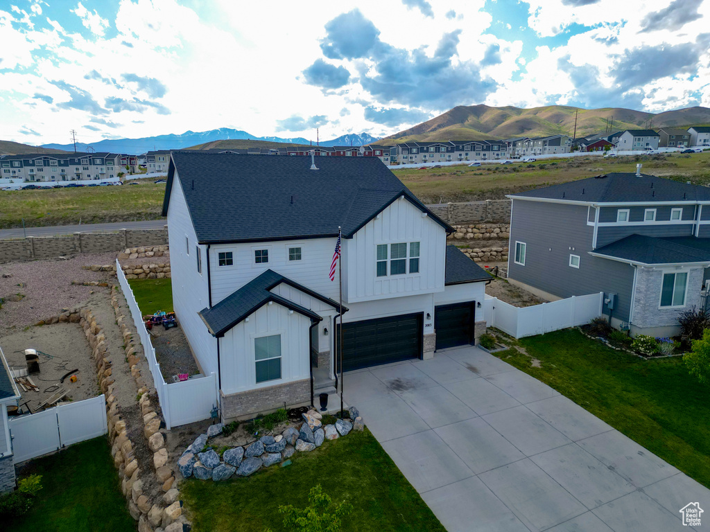 View of front facade featuring board and batten siding, a mountain view, driveway, roof with shingles, and an attached garage