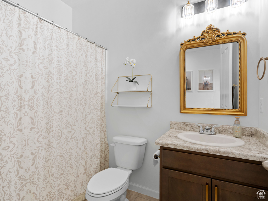 Bathroom with toilet, vanity, tile patterned floors, and baseboards