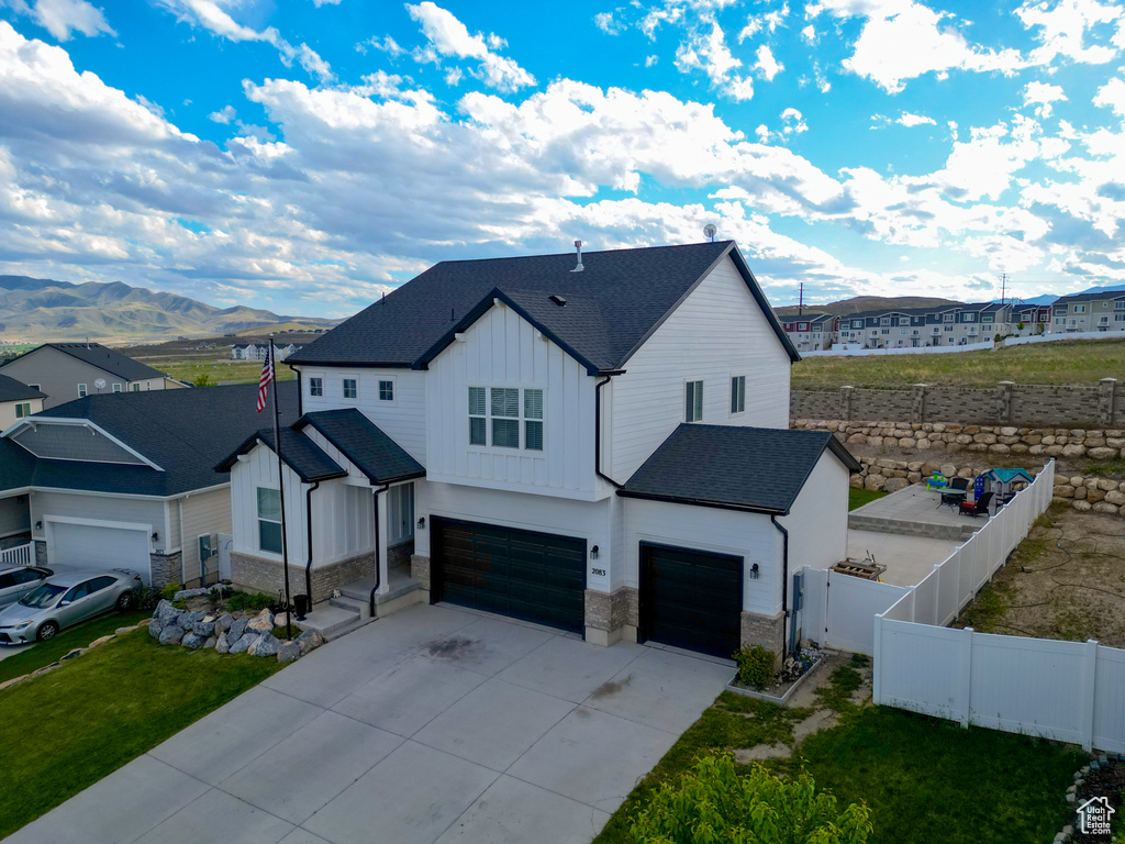 Modern farmhouse style home with board and batten siding, an attached garage, stone siding, and a mountain view