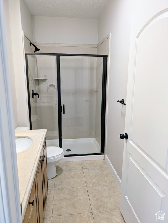 Full bath with a stall shower, vanity, toilet, and marble look tiles