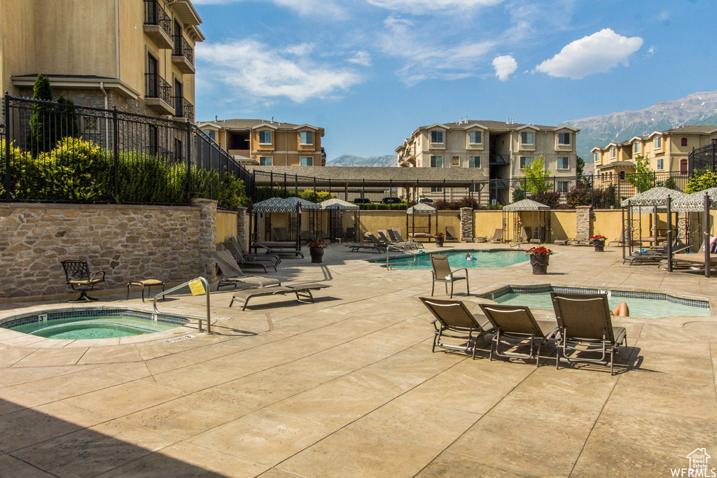 Community pool with a community hot tub, a residential view, a patio, and a mountain view
