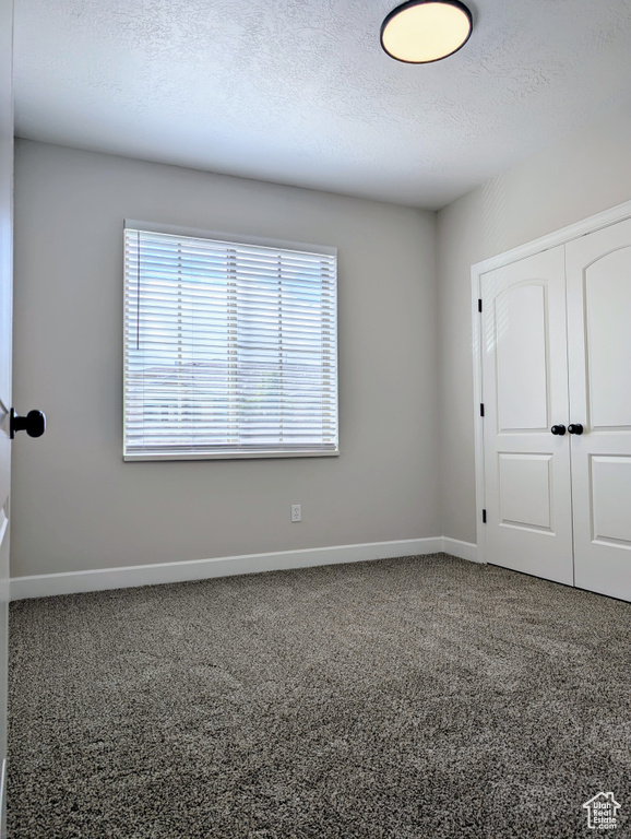 Unfurnished bedroom featuring a closet, baseboards, carpet flooring, and a textured ceiling