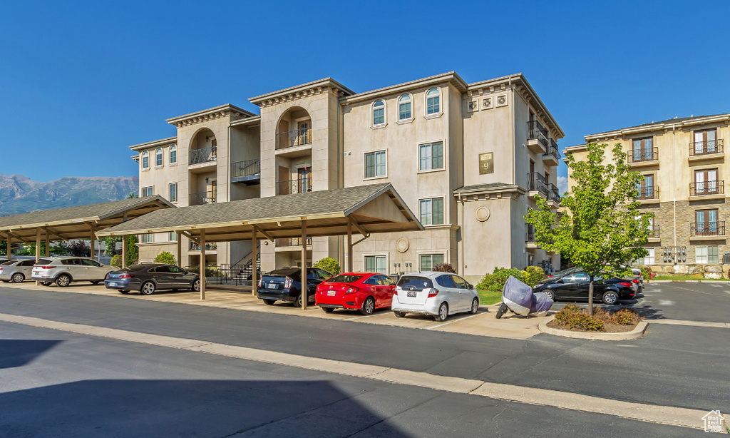 View of property featuring covered and uncovered parking and a mountain view