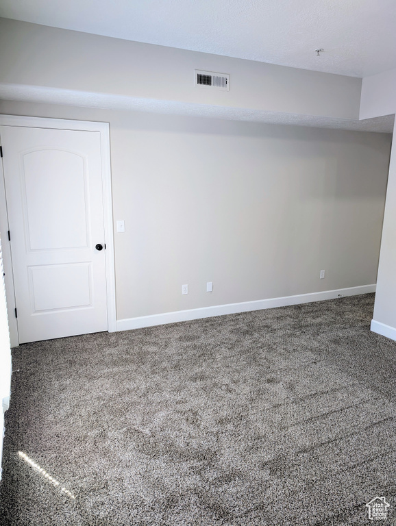 Carpeted spare room featuring baseboards and fire sprinkler in ceiling