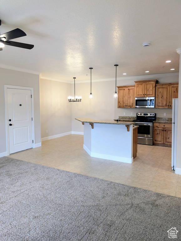 Kitchen with appliances with stainless steel finishes, a breakfast bar area, ceiling fan, brown cabinets, and light tile patterned floors