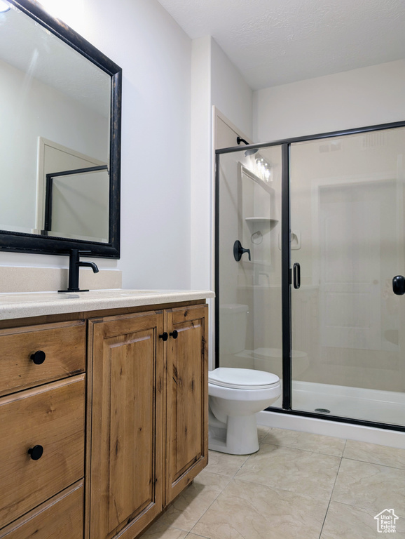 Bathroom with a shower stall, vanity, toilet, and tile patterned flooring